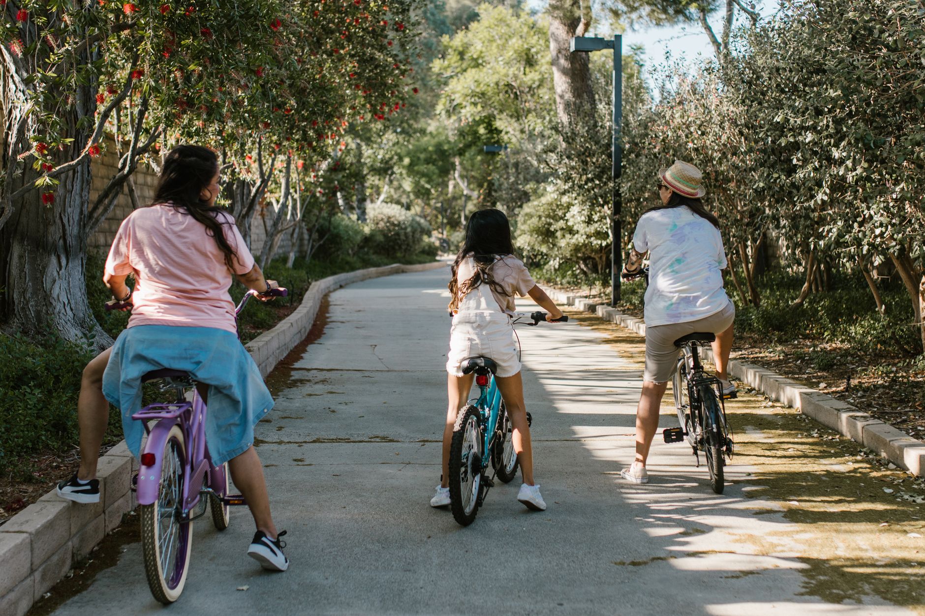 Família pedalando em caminho arborizado